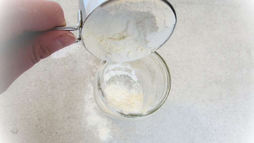 mąka wsypywana do słoika na łatwy zakwas na wypieki