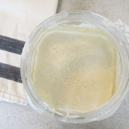 łatwy zakwas na wypieki w słoju i łyżka drewniana na blacie