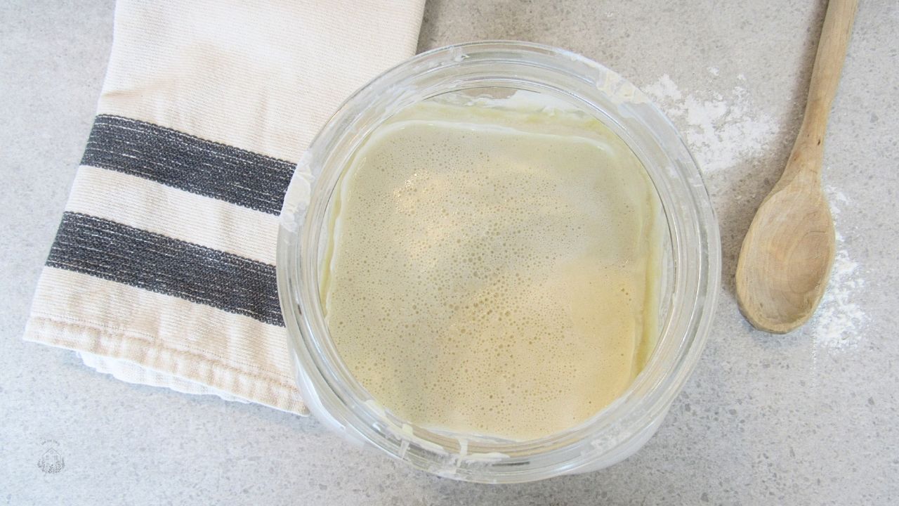 łatwy zakwas na wypieki w słoju i łyżka drewniana na blacie