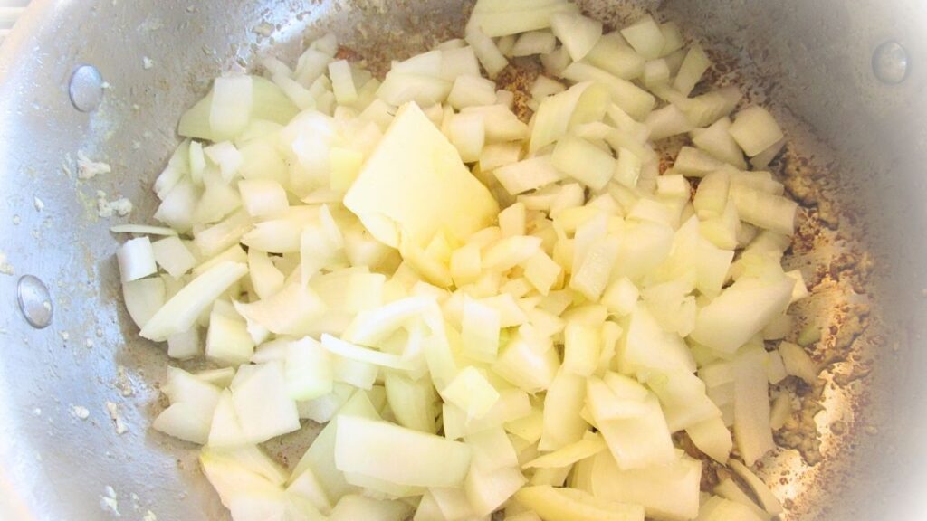 pokrojona cebulka na patelni na indyjską potrawkę z kurczaka