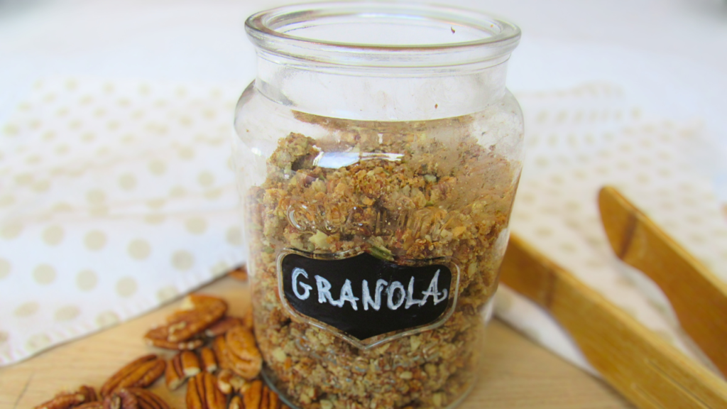 słoik wypełniony granolą i rozsypane orzechy pekan