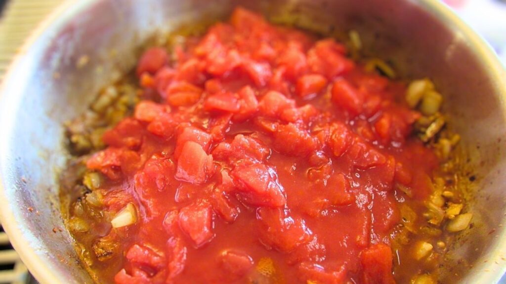 pomidory z puszki na patelni na indyjską potrawkę z kurczaka