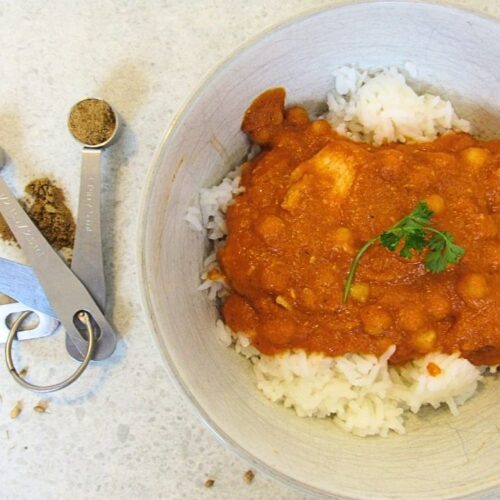 miska z ryżem i indyjska potrawka z kurczaka oraz łyżeczki z przyprawami garam masala, chilli i kolendra