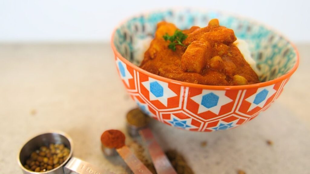 miska z ryżem i indyjska potrawka z kurczaka oraz łyżeczki z przyprawami