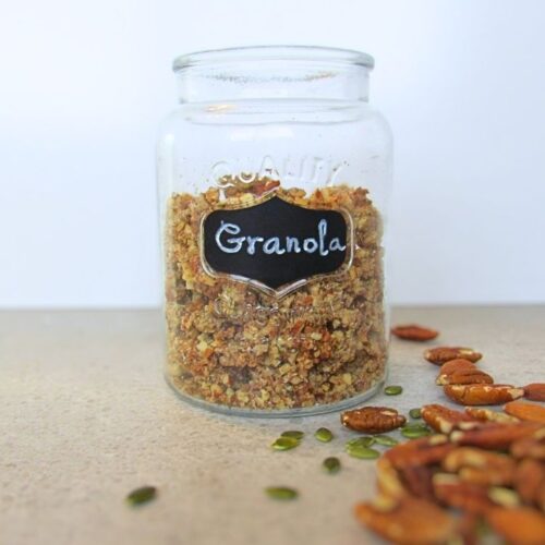zdrowa granola w słoiku z rozsypanymi orzechami i pestkami dyni