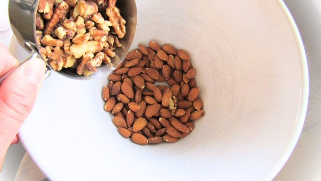 ręka wrzucająca orzechy do miski