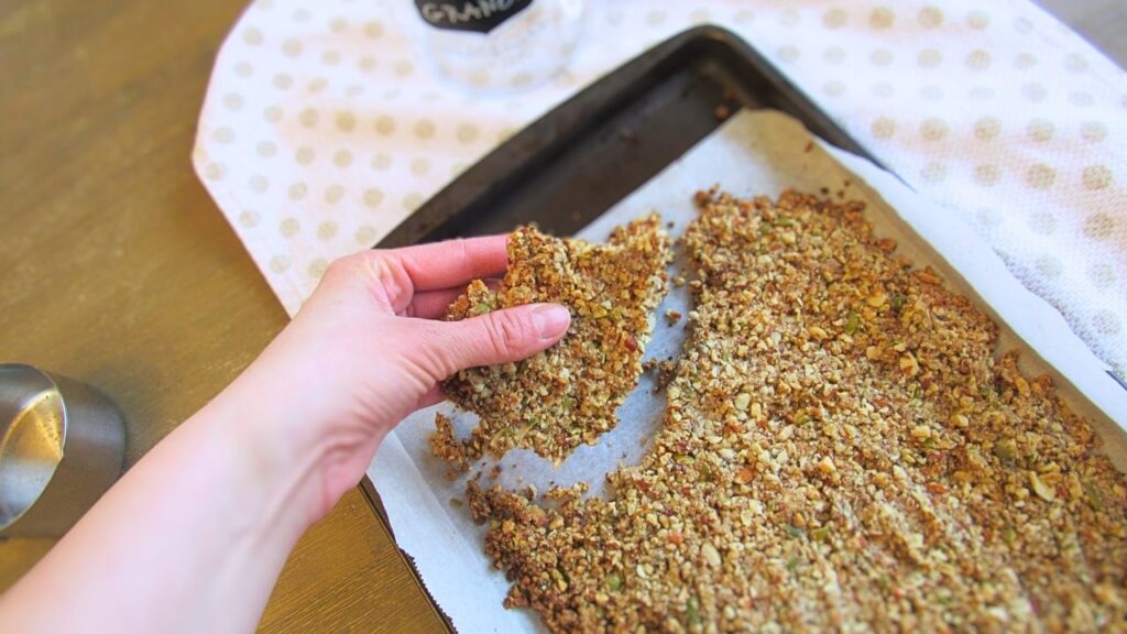 ręka łamiąca upieczoną granolę na mniejsze kawałki