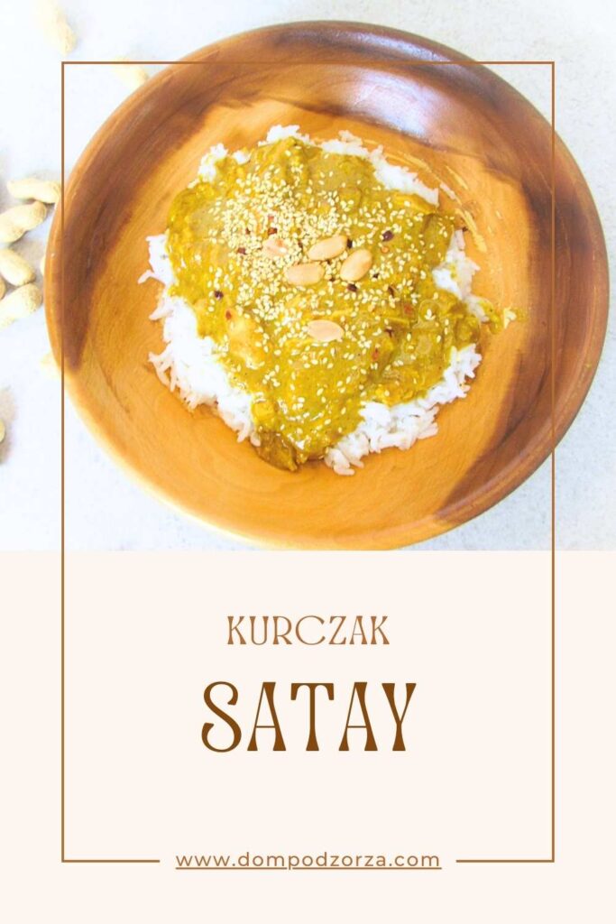 kurczak satay w drewnianej misce z rozsypanymi orzechami laskowymi wokół