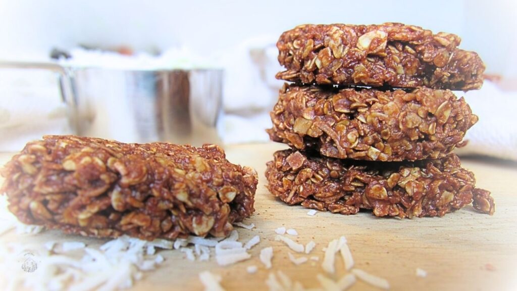 szybkie ciastka bez pieczenia bezglutenowe na drewnianej powierzchni i miarka z kokosem w tle