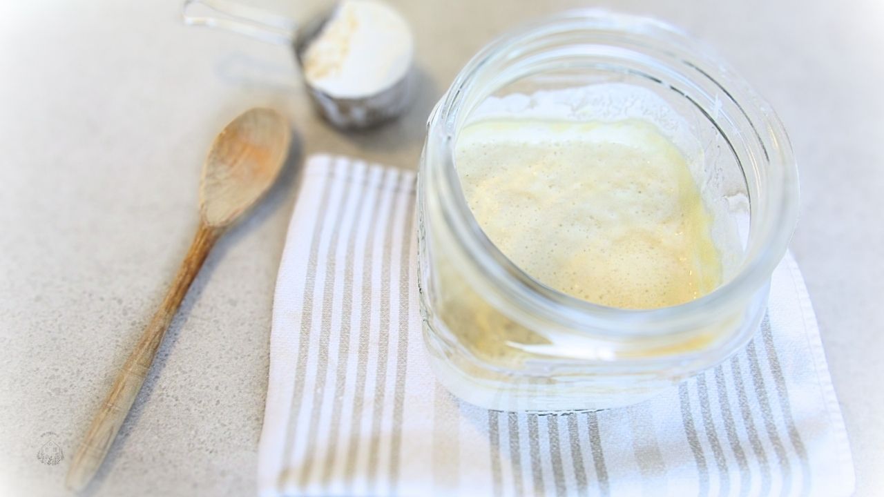 zakwas na wypieki w słoju na ścierce z łyżką i mąką w tle