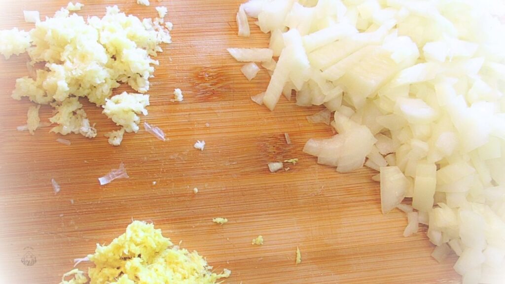 pokrojona cebula, czosnek i imbir na desce drewnianej