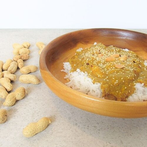 kurczak satay w drewnianej misce z rozsypanymi orzechami laskowymi wokół