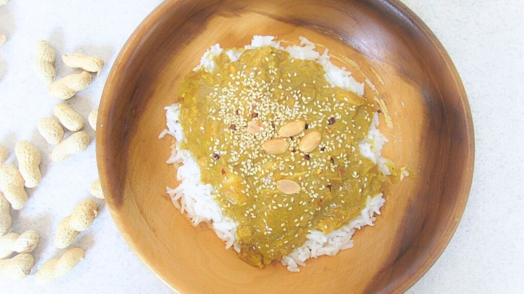 kurczak satay w drewnianej misce z rozsypanymi orzechami laskowymi wokół