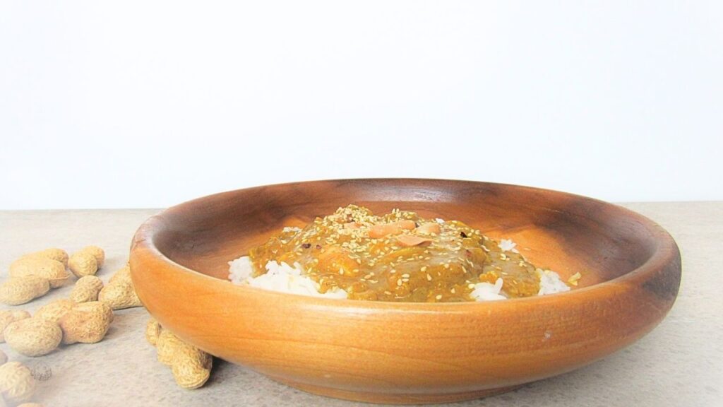 kurczak satay w drewnianej misce z rozsypanymi orzechami laskowymi wokół