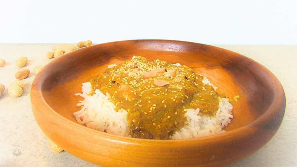 kurczak satay w drewnianej misce z rozsypanymi orzechami laskowymi wokół