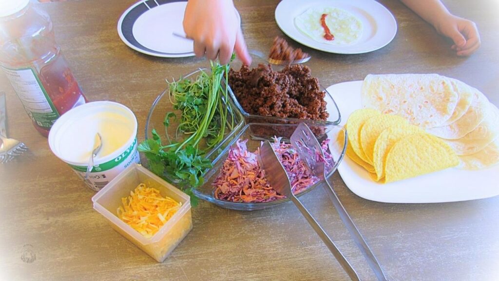 ręka sięgająca po dodatki do tacos