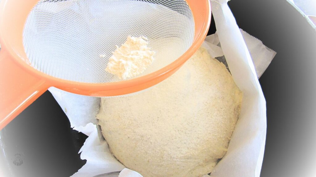 przyprószanie ciasta mąką przez sitko na tradycyjny chleb na zakwasie