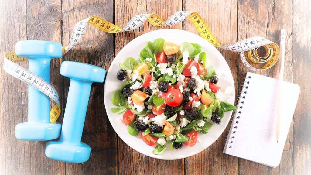 miska z sałatką, a obok ciężarek i taśma mierząca