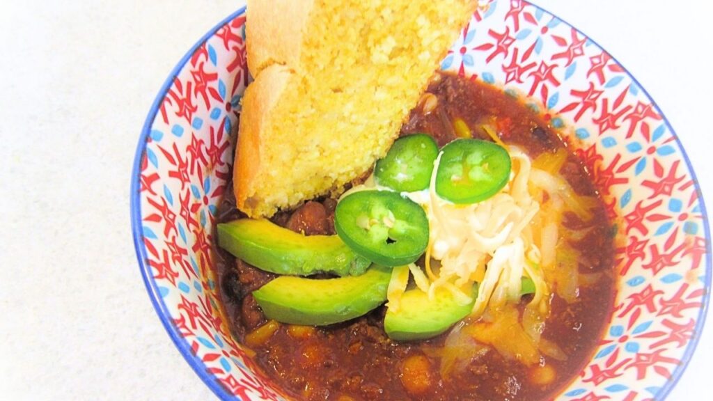 chili con carne w misce z dodatkami i chlebem kukurydzianym