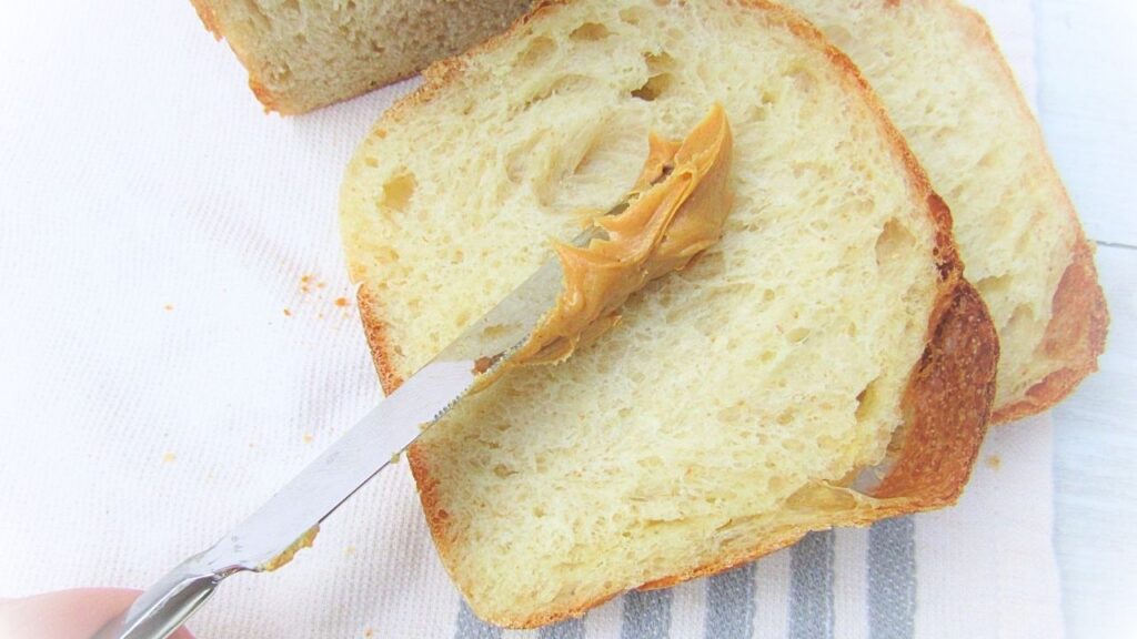 nóż smaruje pajdę chleba tostowego na zakwasie