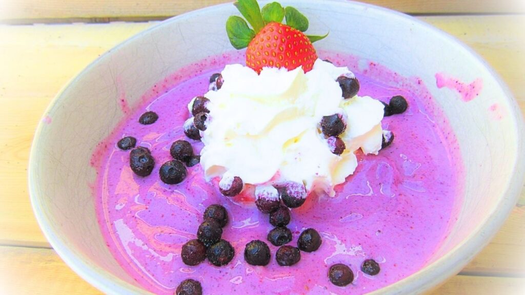 koktajlowa misa z truskawkami i jagodami przyozdobiona jagodami i truskawkami oraz bitą śmietaną