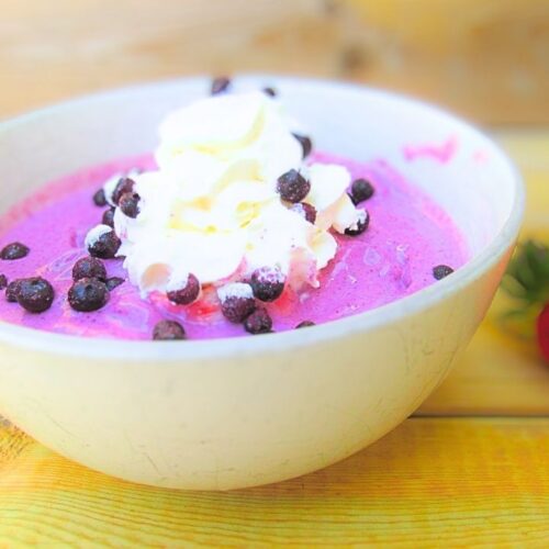 koktajlowa misa z truskawkami i jagodami przyozdobiona jagodami oraz bitą śmietaną