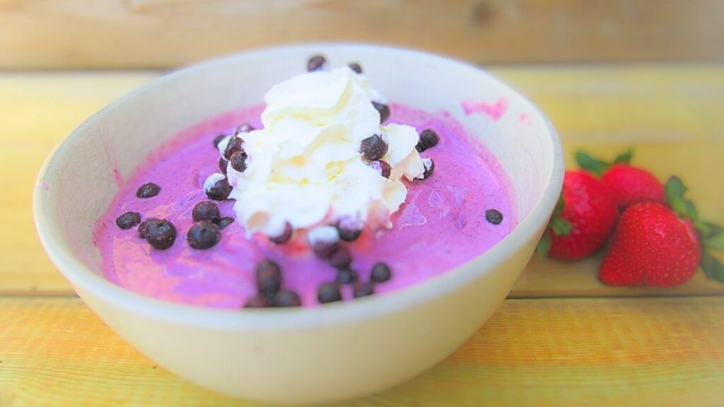 koktajlowa misa z truskawkami i jagodami przyozdobiona jagodami oraz bitą śmietaną