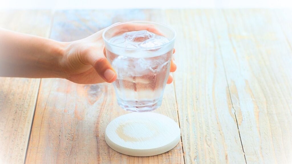 ręka trzyma szklankę wody nad stołem