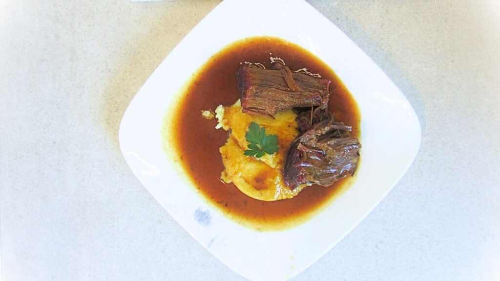 pieczeń wołowa na białym talerzu w sosie z ziemniaczkami