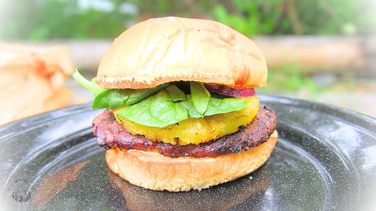 burger wołowy po hawajsku z ananasem na czarnym talerzu metalowym