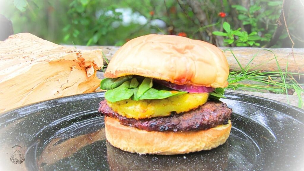 burger wołowy po hawajsku z ananasem na czarnym talerzu metalowym