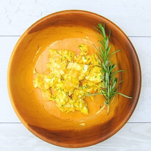 jajecznica z rozmarynem na talerzu drewnianym