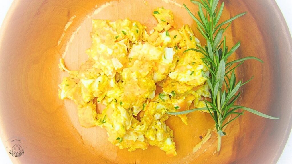 jajecznica z rozmarynem w drewnianej misce z rozmarynem świeżym na boku