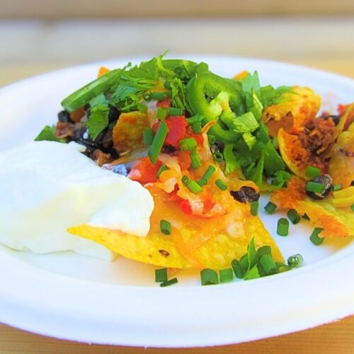 meksykańskie nachos z dodatkami na białym talerzu